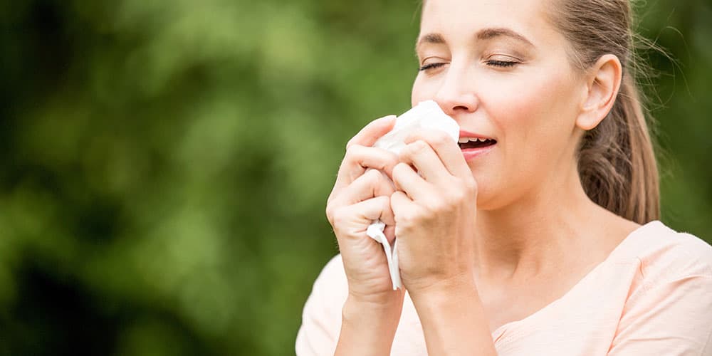 Junge Frau mit Allergie hustet in Taschentuch