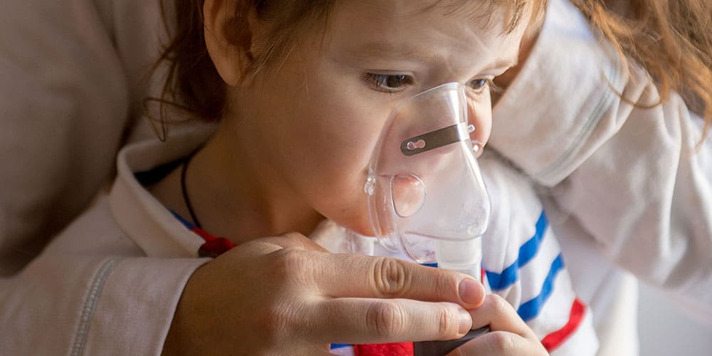 Ein kleiner Junge inhaliert mit einem Inhalationsgerät
