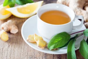 Eine Tasse Tee mit Zitrone, Ingwer und Kräutern auf einem Tisch