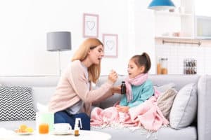 Mutter gibt ihrer Tochter einen Löffel Hustensaft