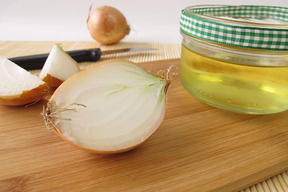 Aufgeschnittne Zwiebel auf einem Tisch neben einem Glas Honig