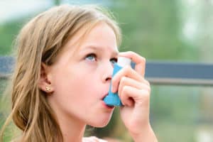 Mädchen inhaliert mit Asthma Spray
