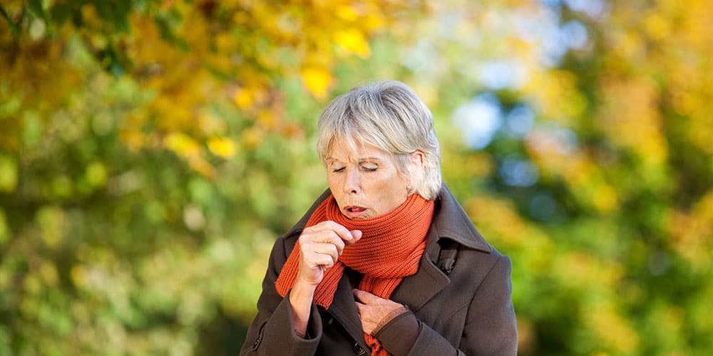 Ältere Dame hustet im Herbst