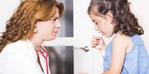 Kleines Mädchen hustet bei einer Ärztin