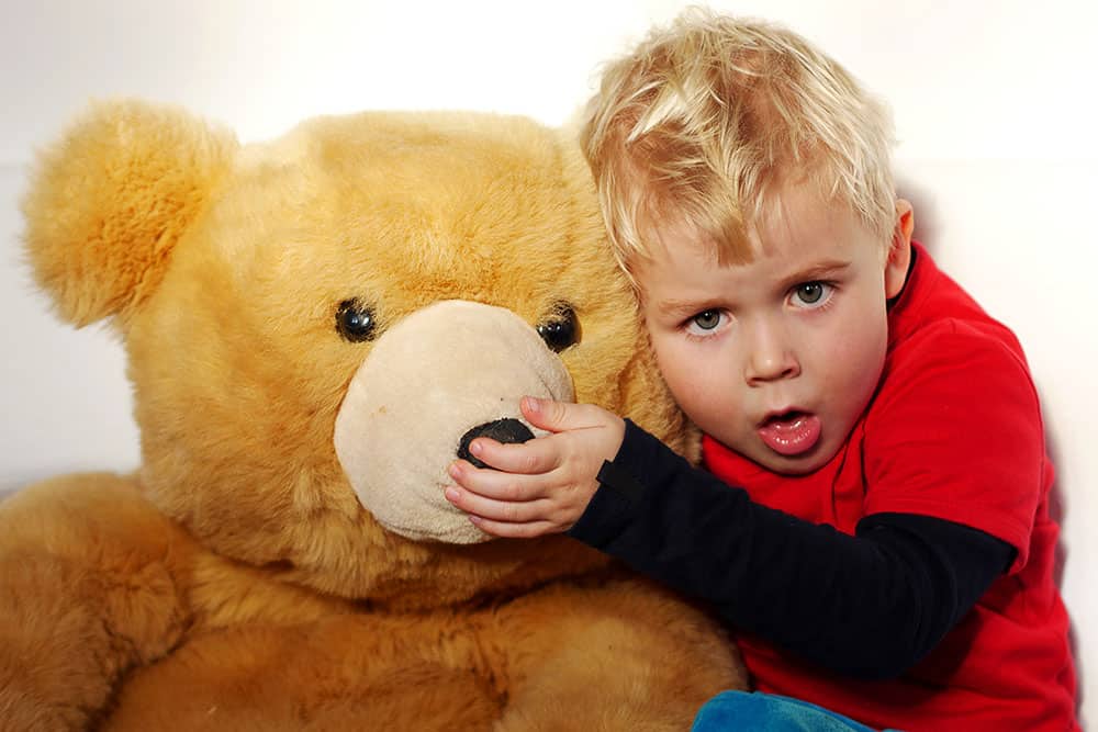 Kleiner Junge mit Teddybär hustet
